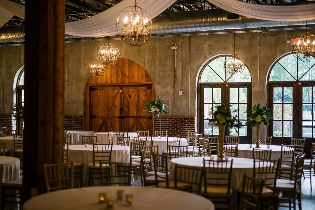 A large room with tables and chairs set up for a wedding reception.