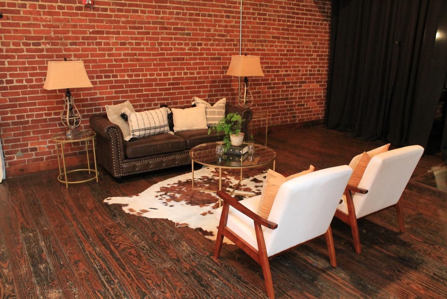 A living room with a couch , chairs , lamps and a cowhide rug.