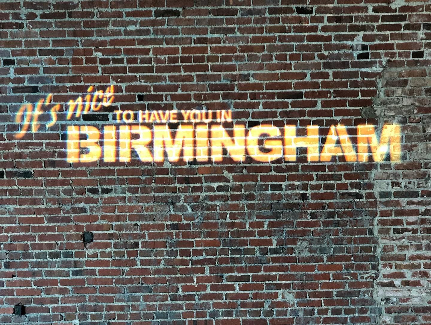 A sign on a brick wall says it 's nice to have you in birmingham
