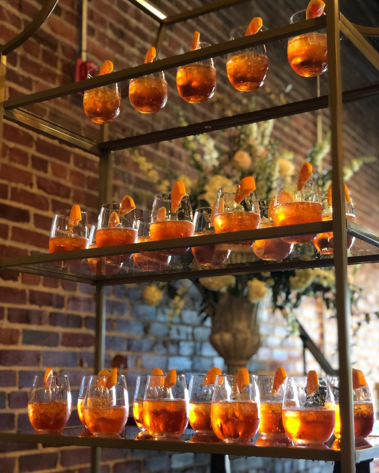 A shelf full of glasses filled with orange liquid