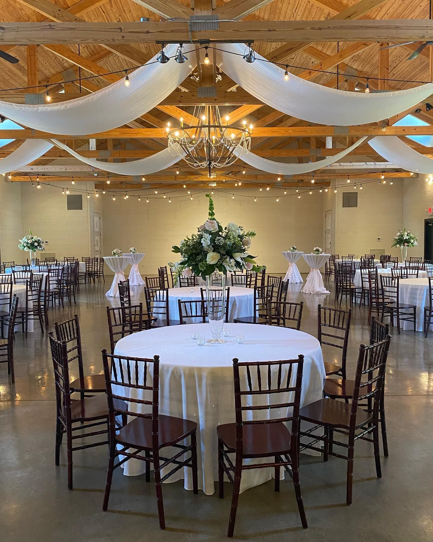 A large room with tables and chairs set up for a wedding reception.