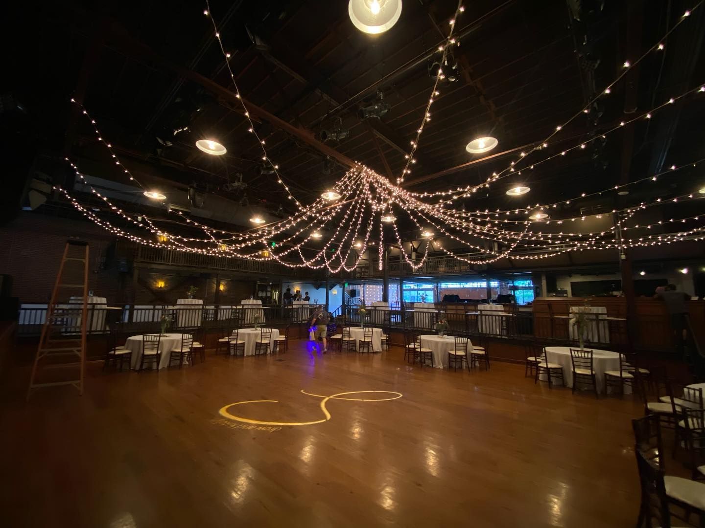 A large room with tables and chairs and string lights hanging from the ceiling.