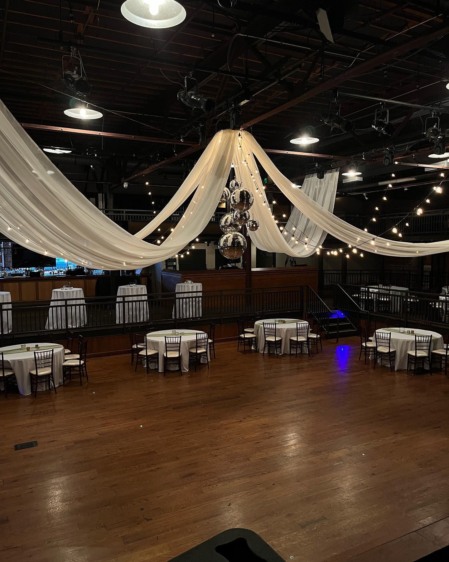 A large room with tables and chairs and a chandelier hanging from the ceiling.