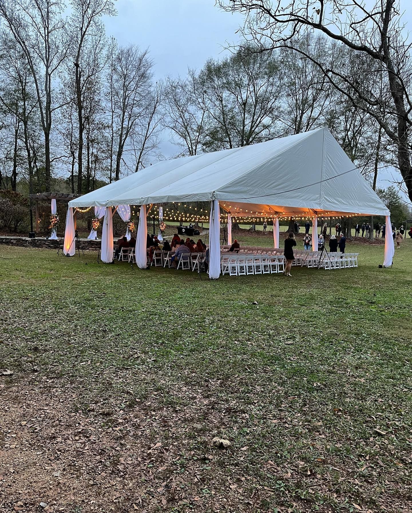 A large white tent is sitting in the middle of a grassy field.