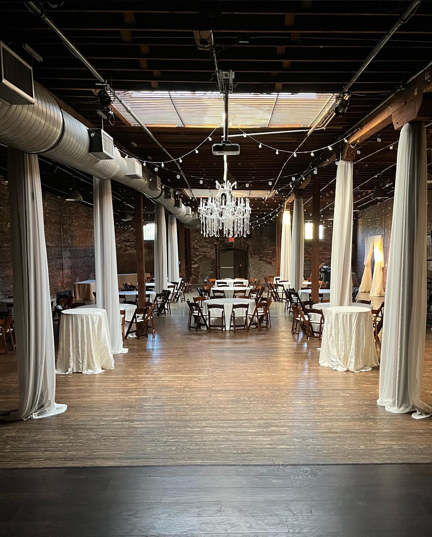 A large room with tables and chairs and a chandelier.