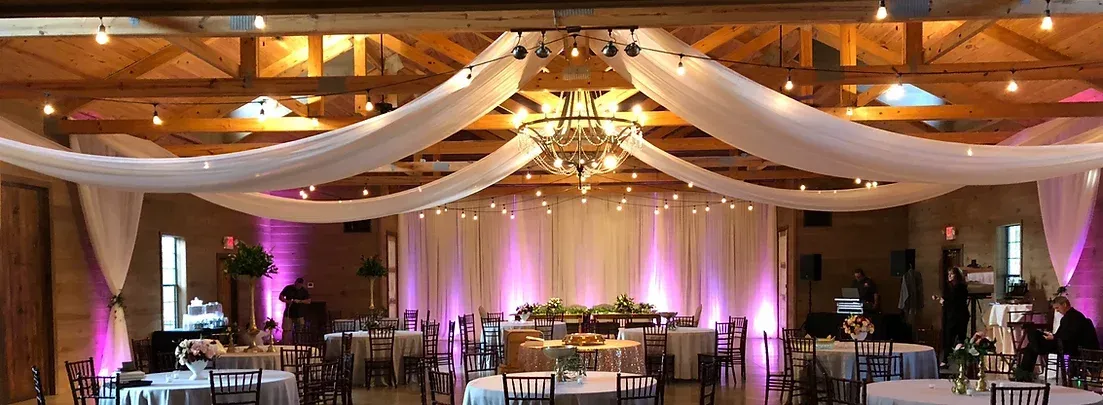 A large room decorated for a wedding reception with tables and chairs.