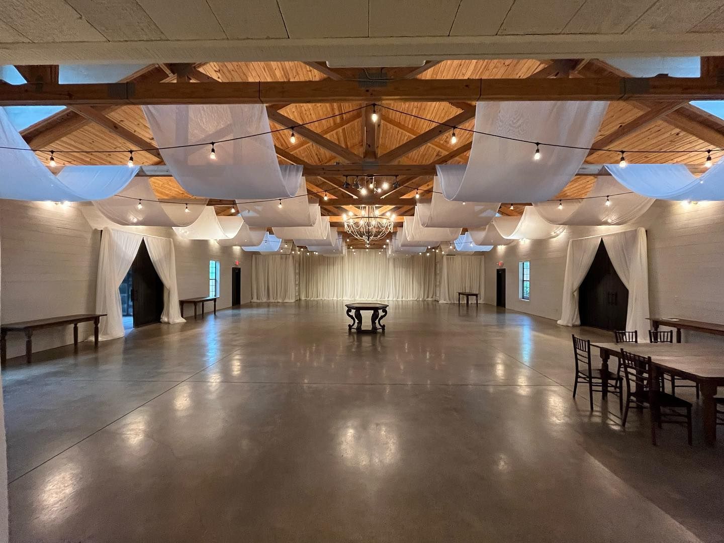 A large empty room with tables and chairs and a chandelier hanging from the ceiling.