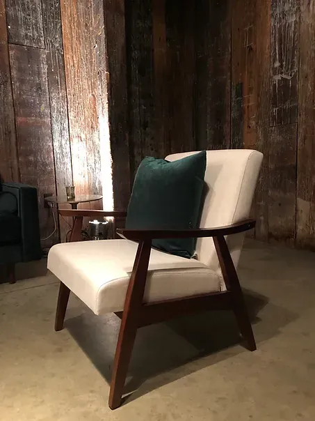 A white chair with a green pillow on it is sitting in a room.