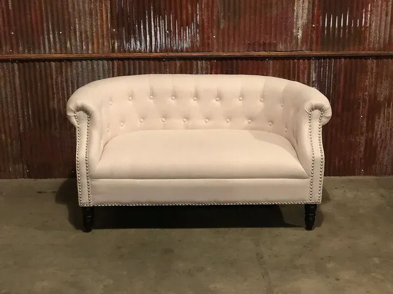 A white couch is sitting in front of a rusty metal wall.