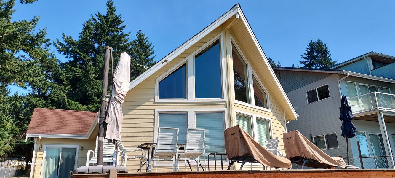 A yellow pressure washer sits on a wet concrete driveway in front of a white garage door.