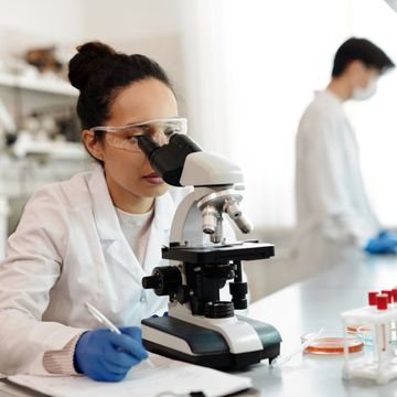 Photo of a woman in a lab using a microscope