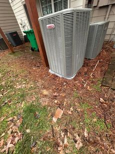 A large air conditioner is sitting on the side of a house.