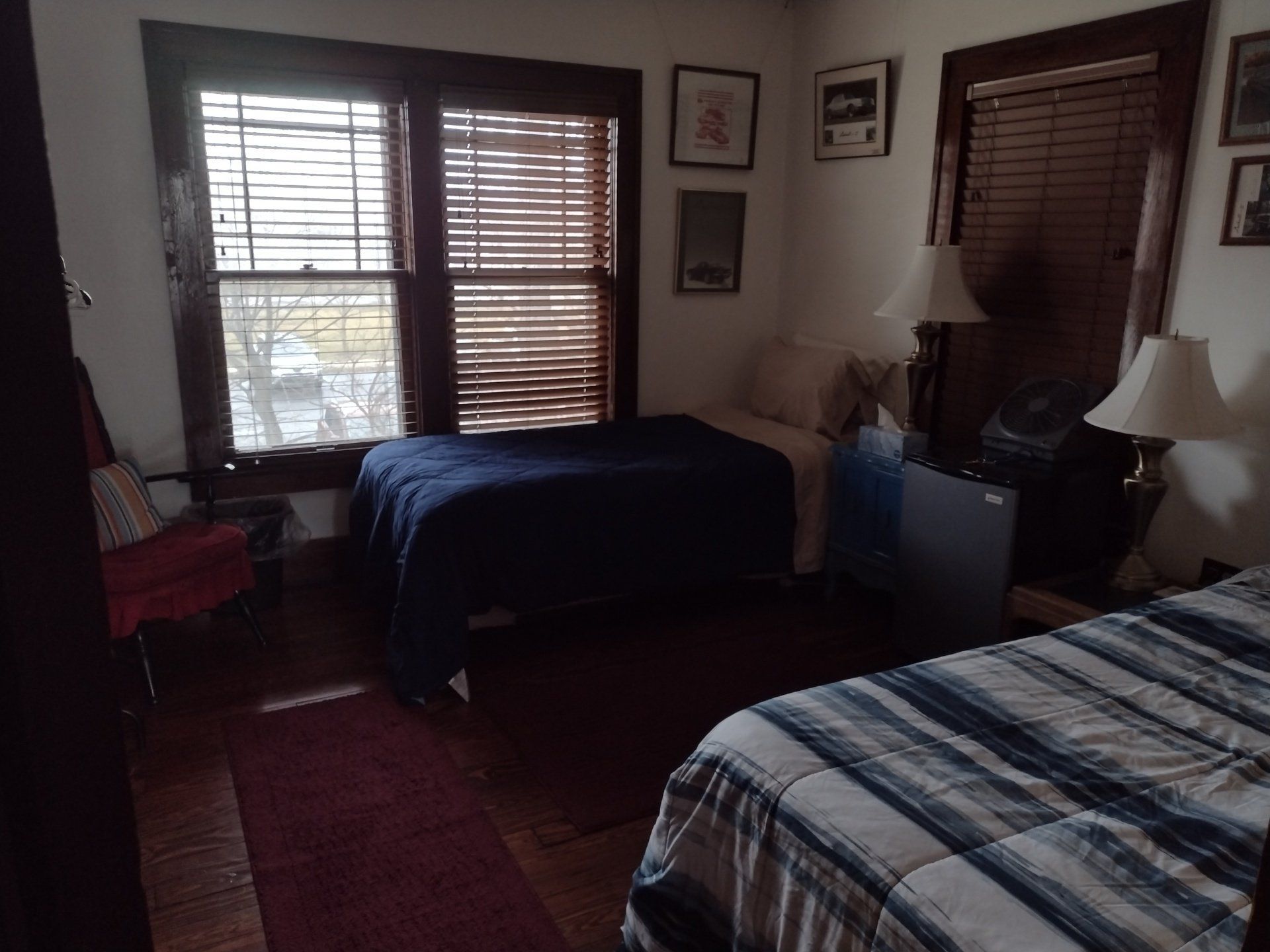 Bedroom with two beds, a window with blinds, and lamps.