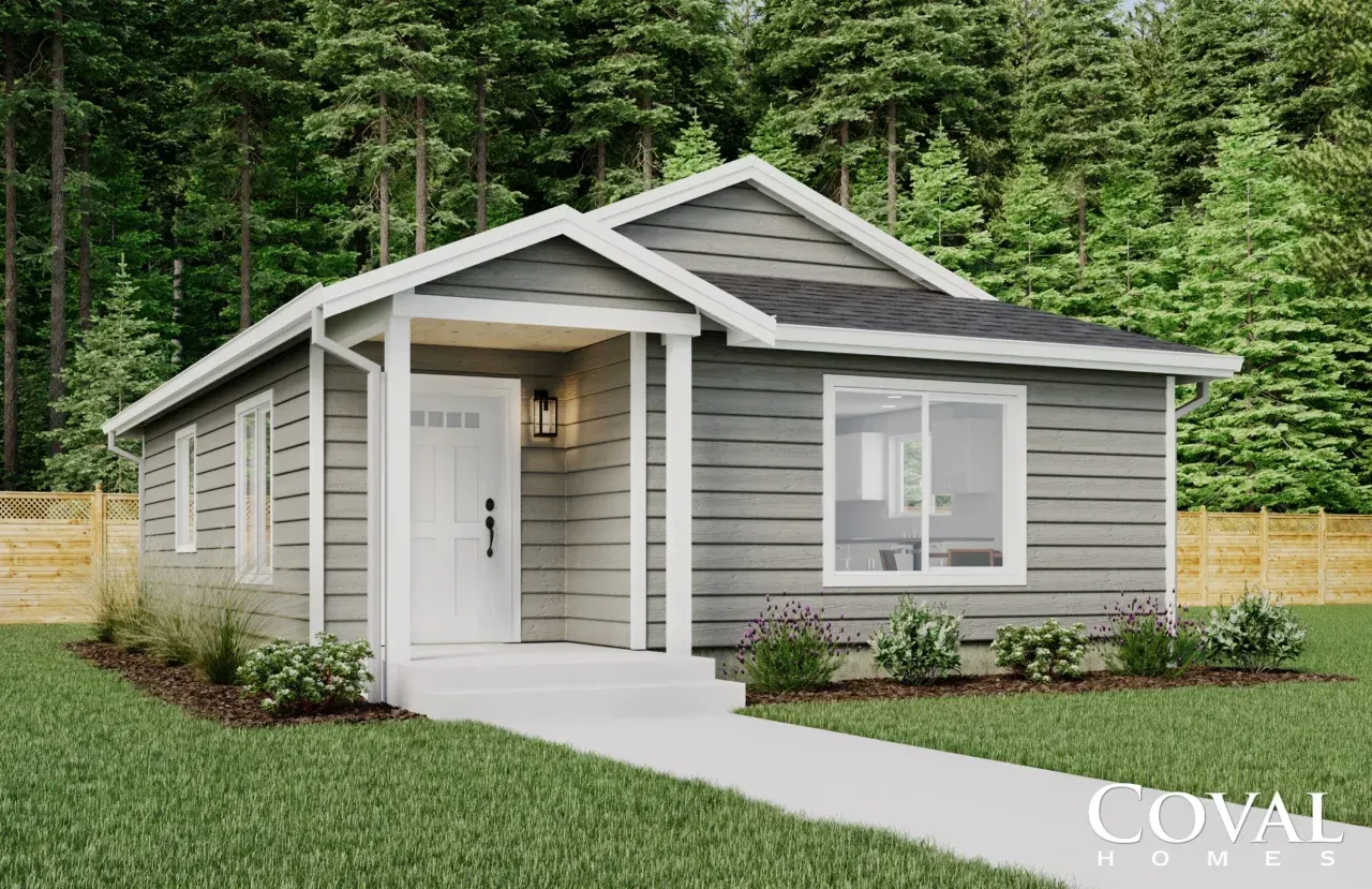 Gray modern single-story house with white trim, front porch, and large windows against a wooded backdrop