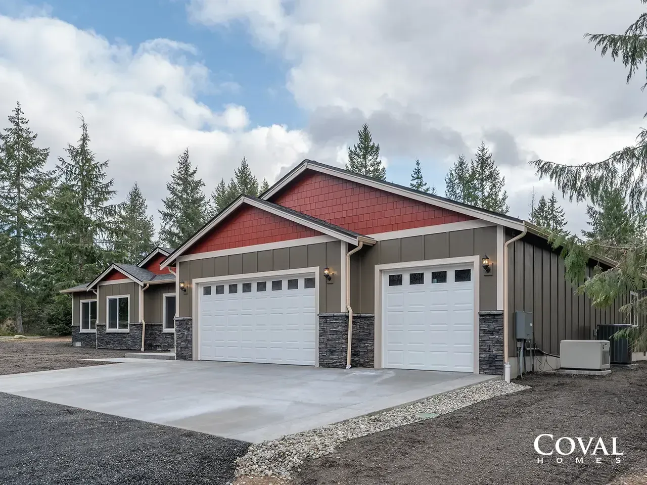 Modern beige garage with red roof, two white garage doors, and stone accents on a concrete driveway.