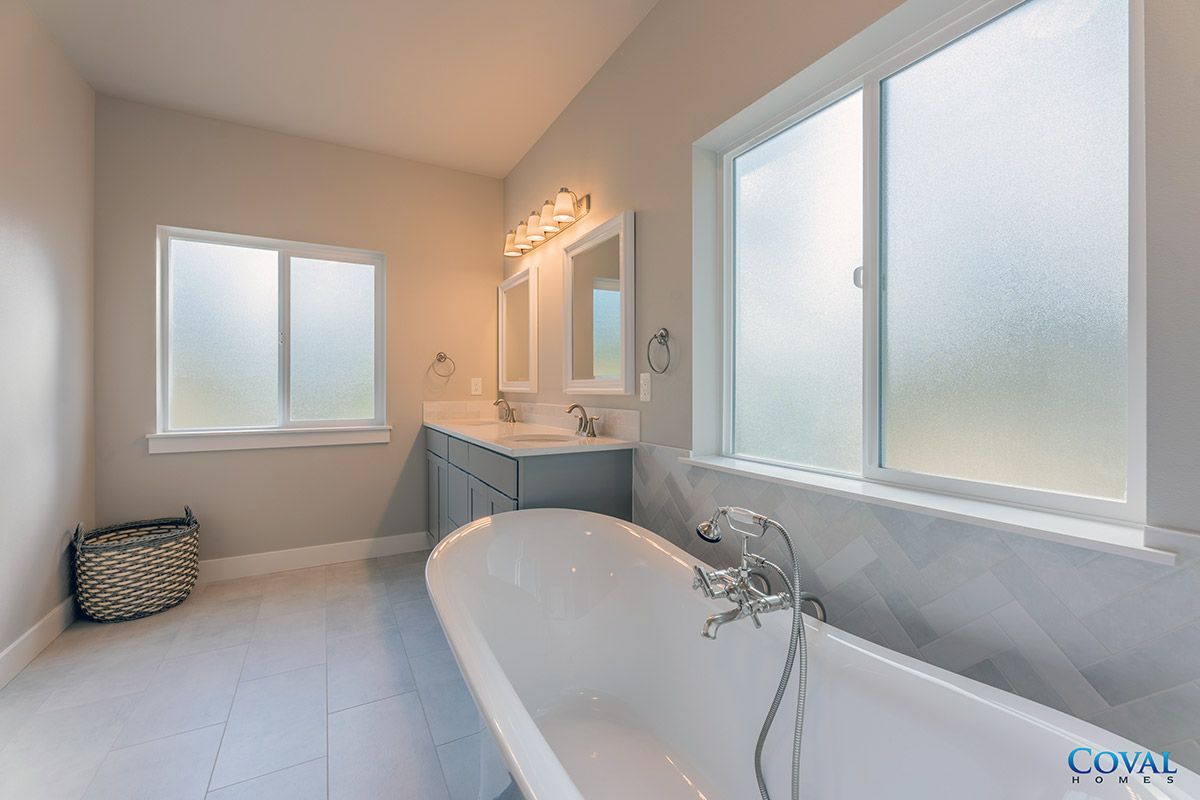 Bright bathroom with a freestanding tub, double vanity, and frosted windows.