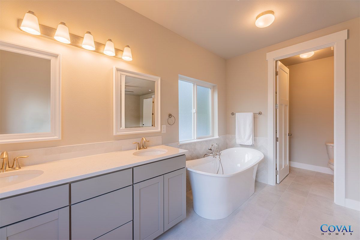 Bright modern bathroom with double vanity, mirrors, and freestanding tub
