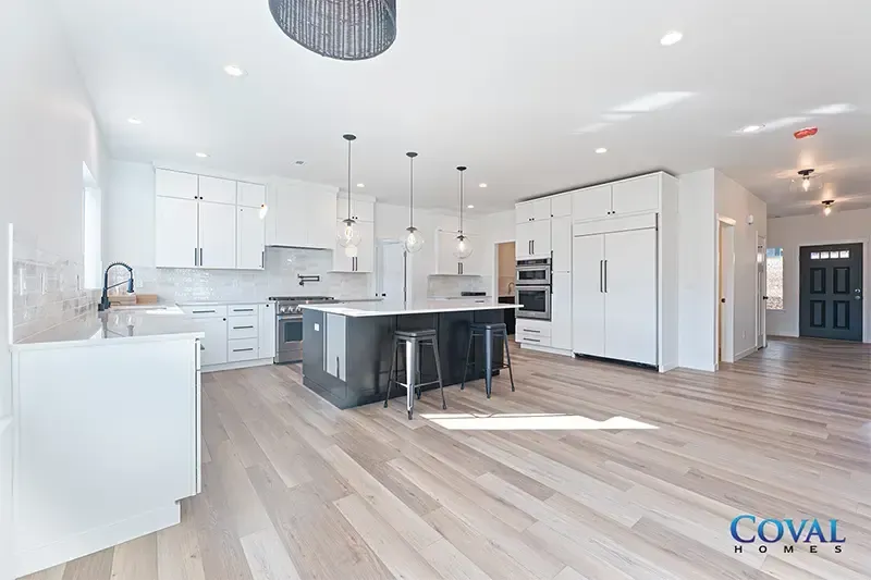 Bright open-plan kitchen and living room with white cabinets, black island, and light wood floors