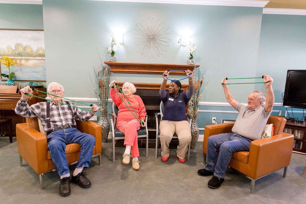 A group of elderly people are doing exercises in a living room.