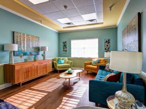 A living room with a couch , chairs , tables and lamps.