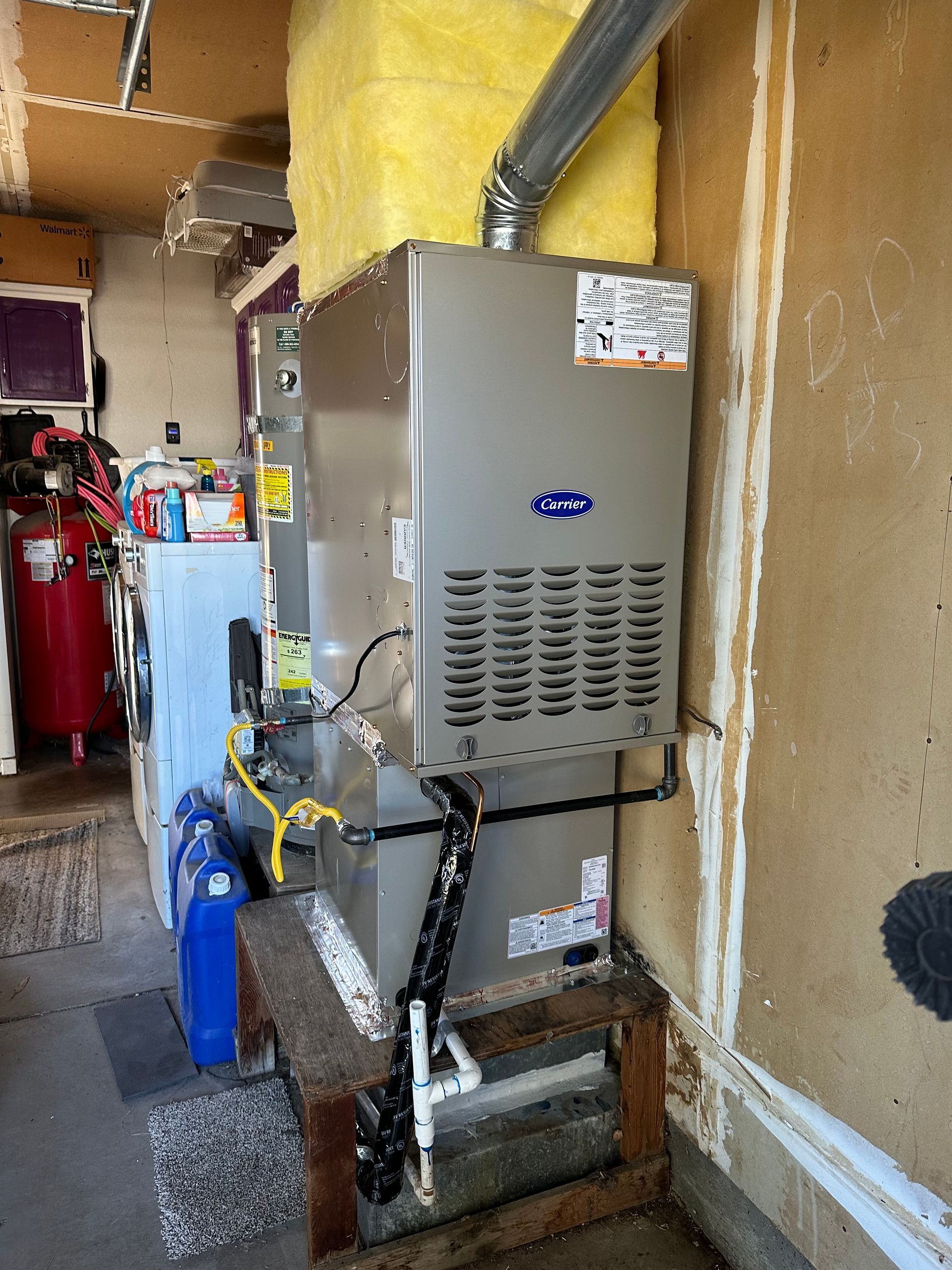 A light gray outdoor residential air conditioning unit sits on a concrete pad against a beige exterior wall.
