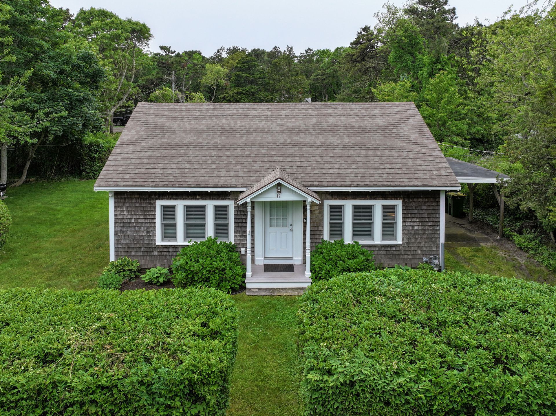 An aerial view of a small house surrounded by trees and bushes.