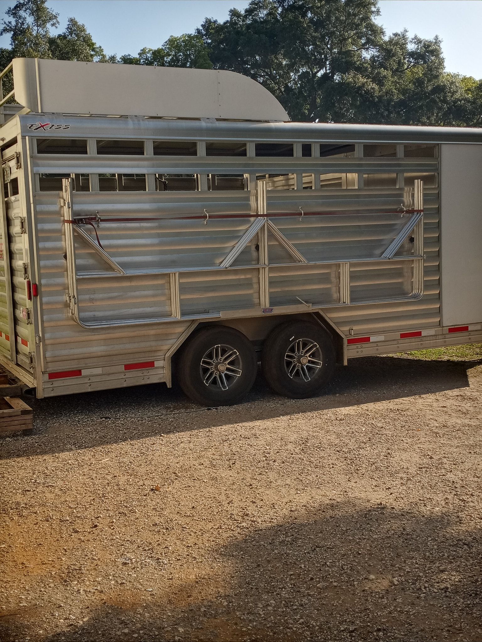 Aluminum horse trailer parked on gravel.