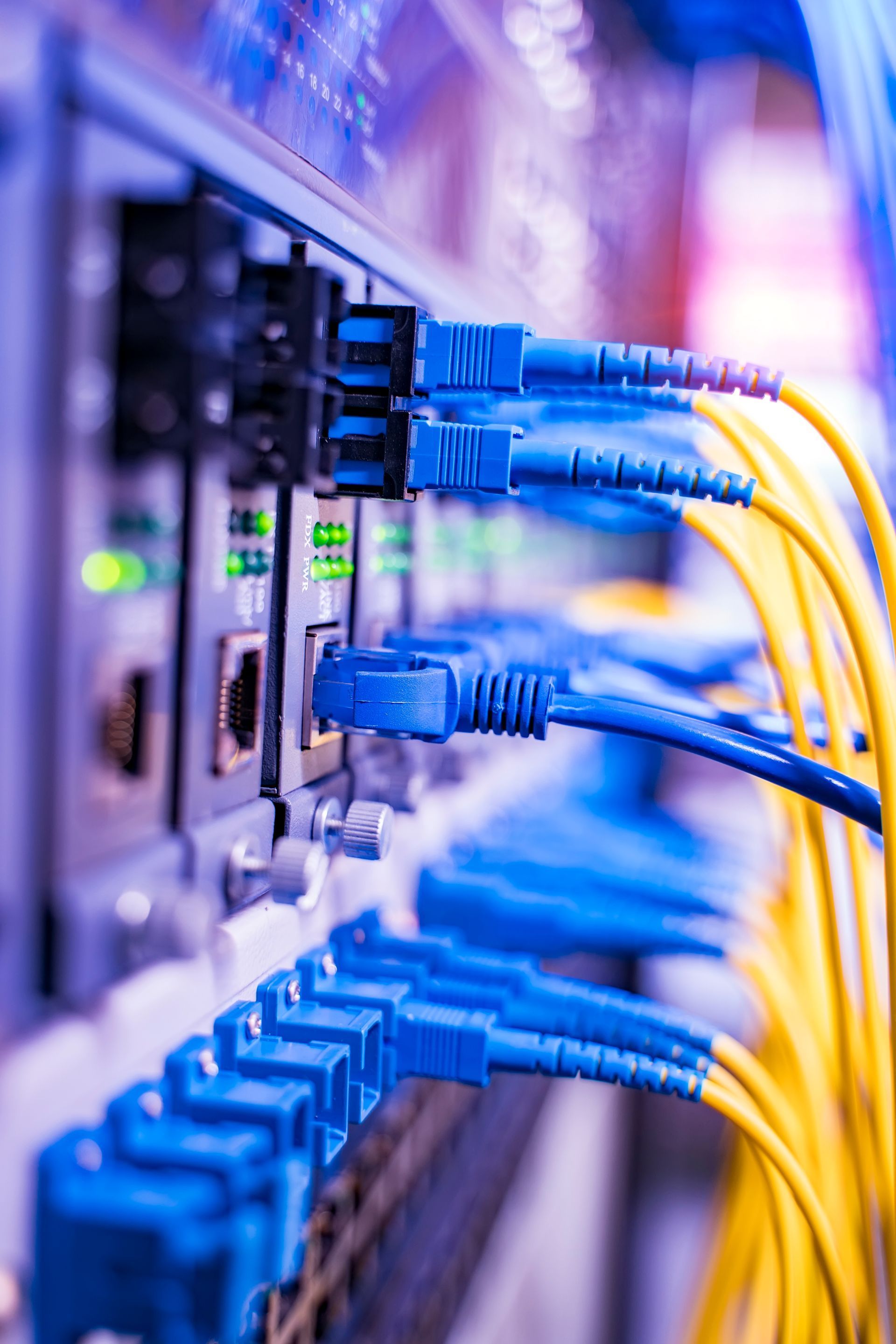 Server rack with orange fiber optic cables lit up.