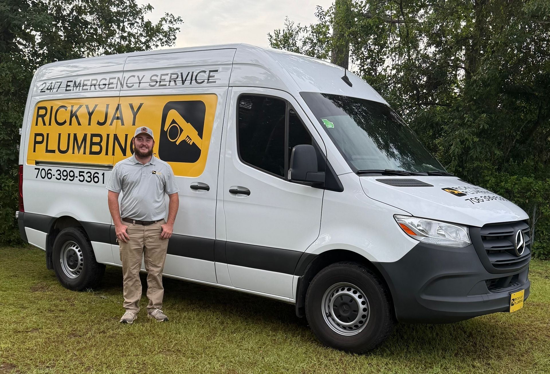 A man is standing in front of a ricky jay plumbing van.