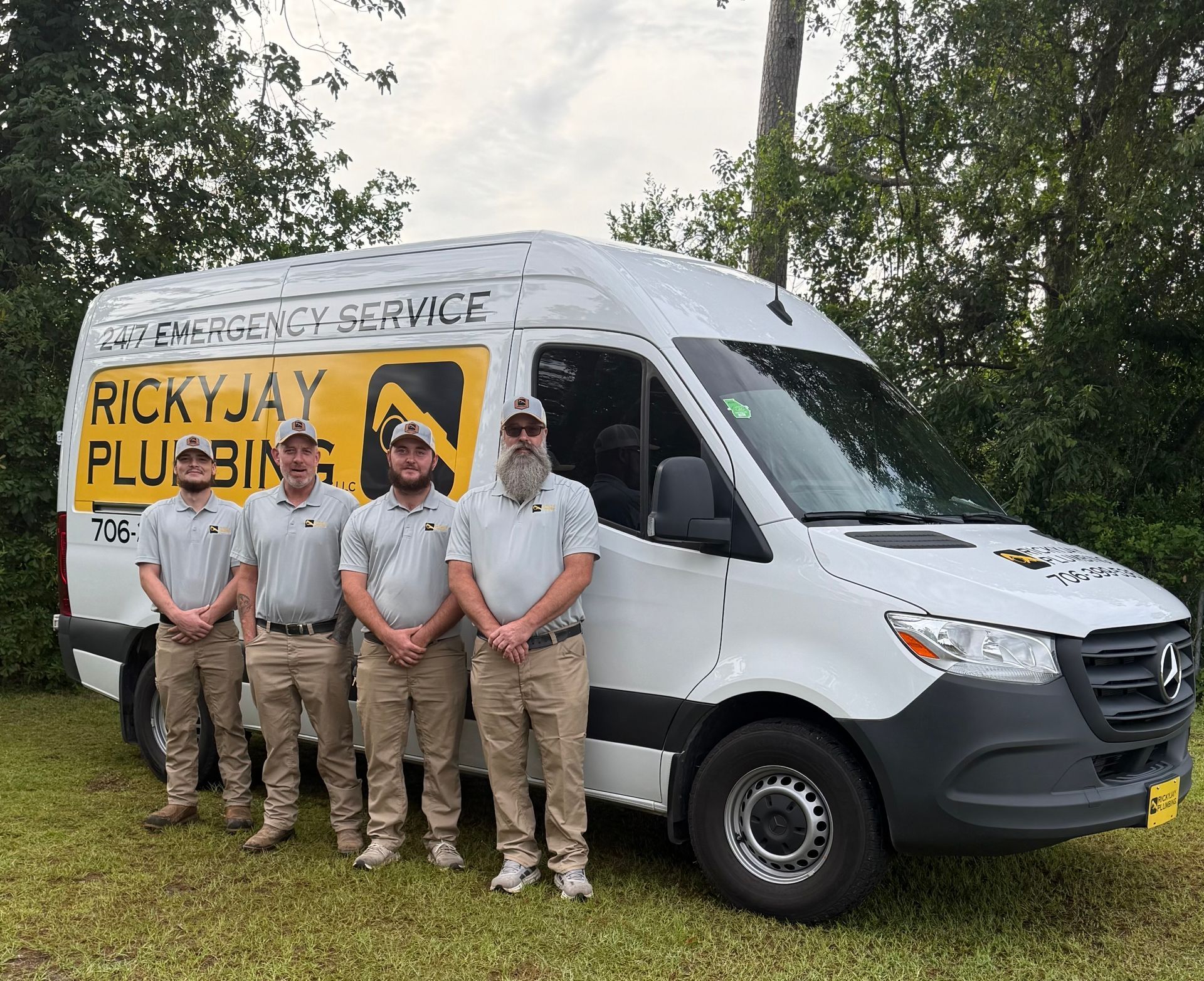 A group of men are standing in front of a ricky jay plumbing van.