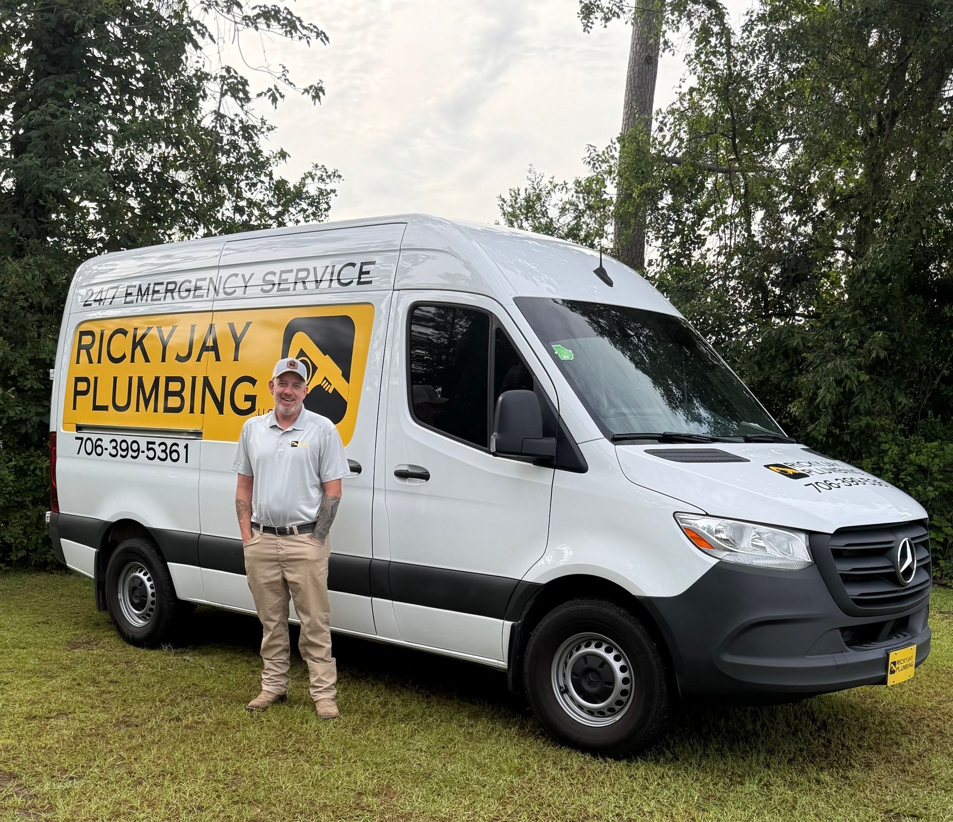 A man is standing in front of a ricky jay plumbing van.
