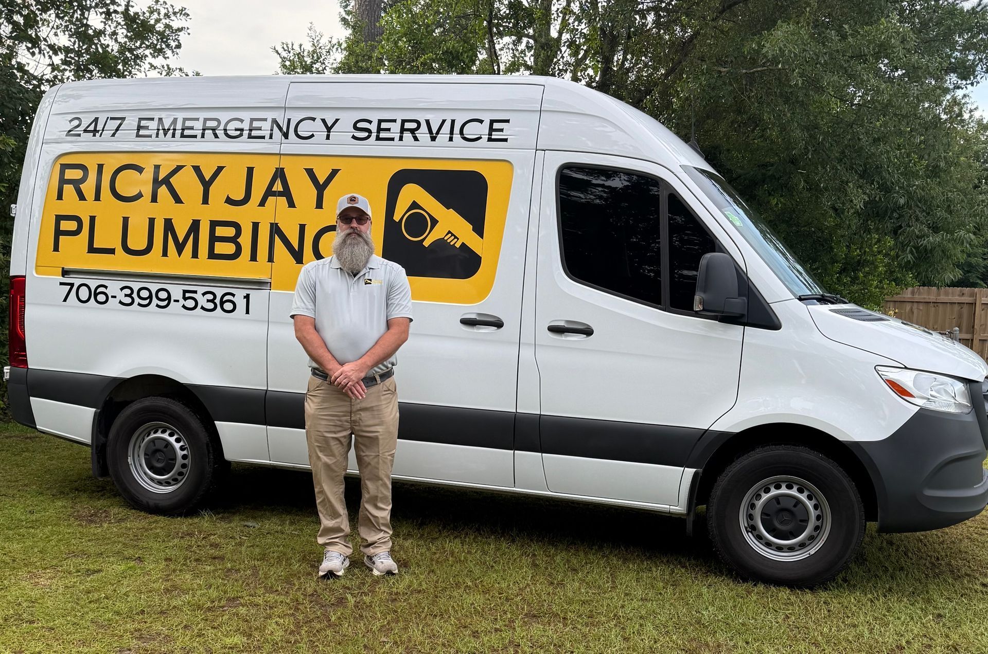 A man is standing in front of a ricky jay plumbing van.
