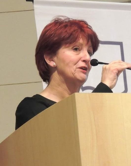 Una mujer pelirroja está hablando por un micrófono.