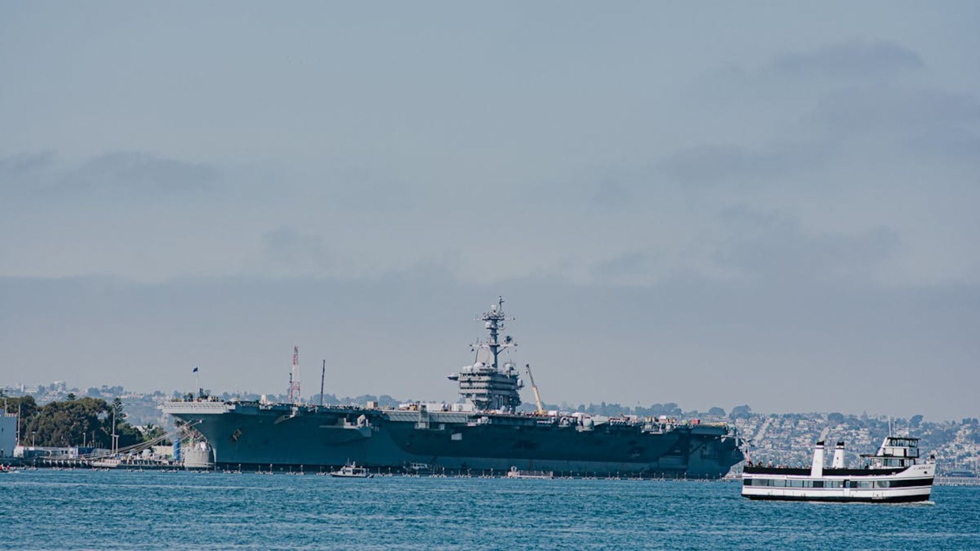 Un gran barco militar flota sobre un cuerpo de agua al lado de un pequeño bote.