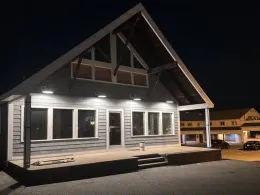 Nighttime exterior of a building with a gray facade, lit with bright overhead lights.