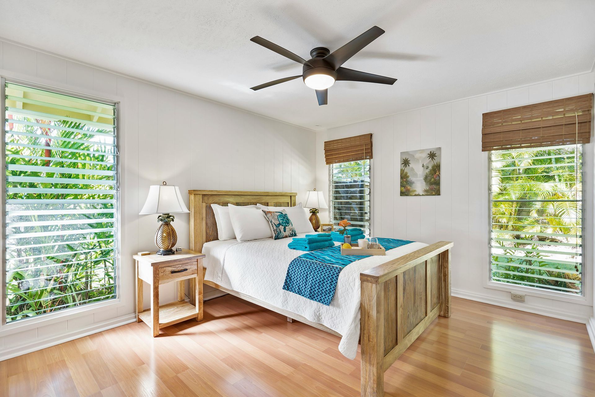 Bedroom with wooden bed, white walls, shuttered windows, and a ceiling fan.