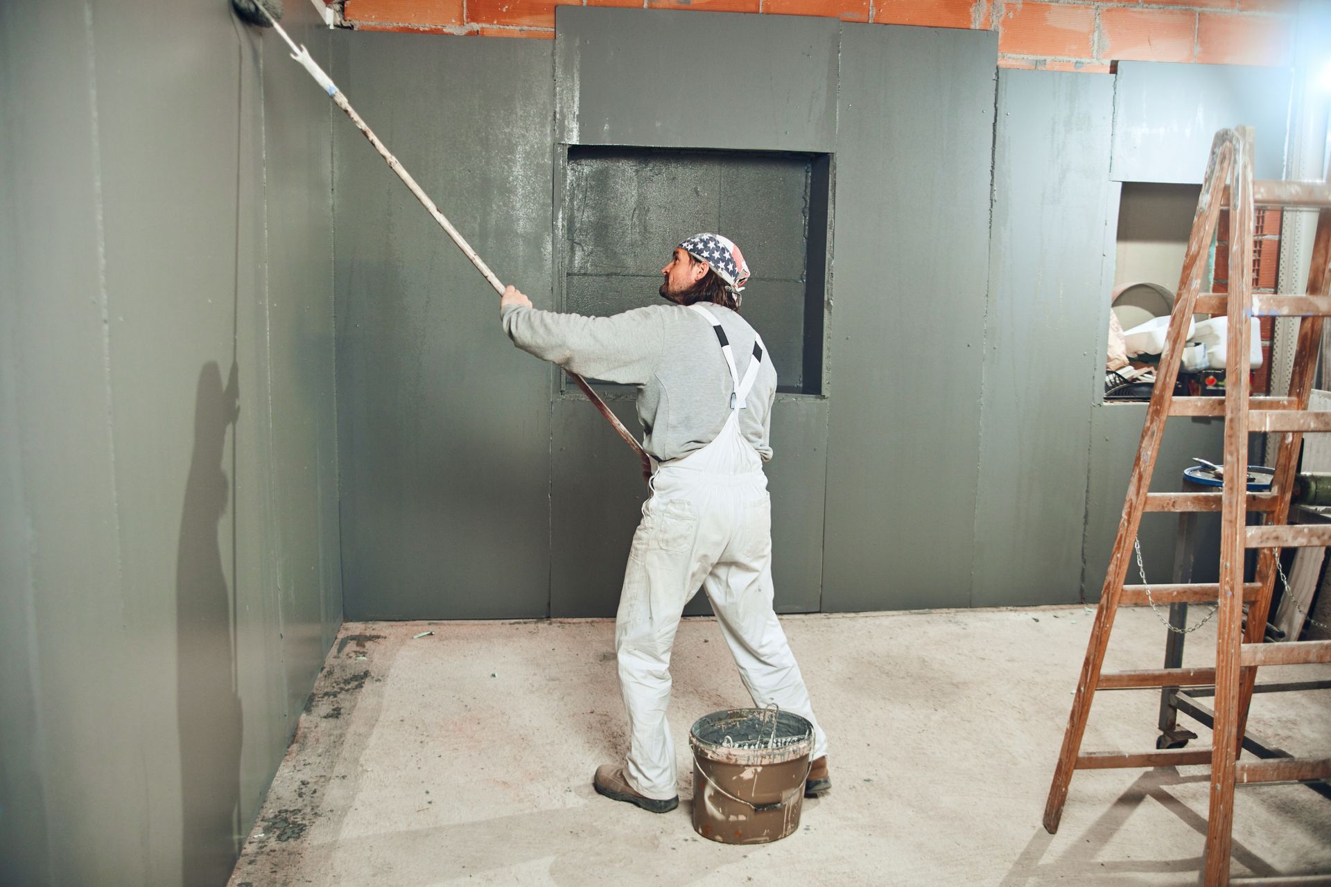 Painter painting walls with a extender roller indoors
