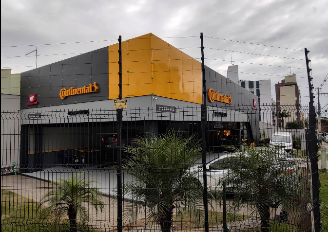 Loja de pneus Continental com fachada preta e amarela, perímetro cercado.