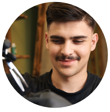 Barber with mustache holding scissors, focused on a haircut in a salon.