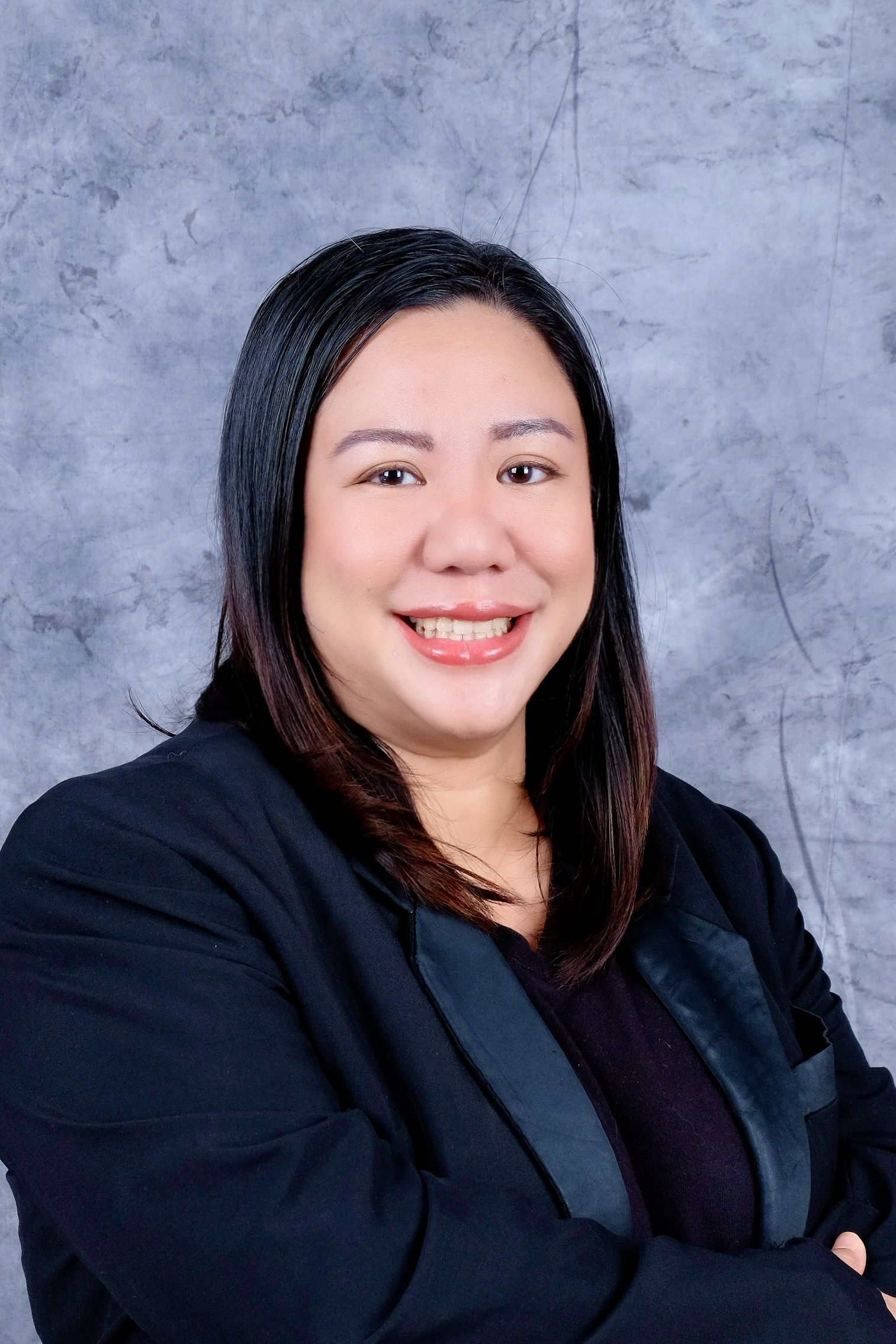 A woman in a suit and white shirt is smiling for the camera.