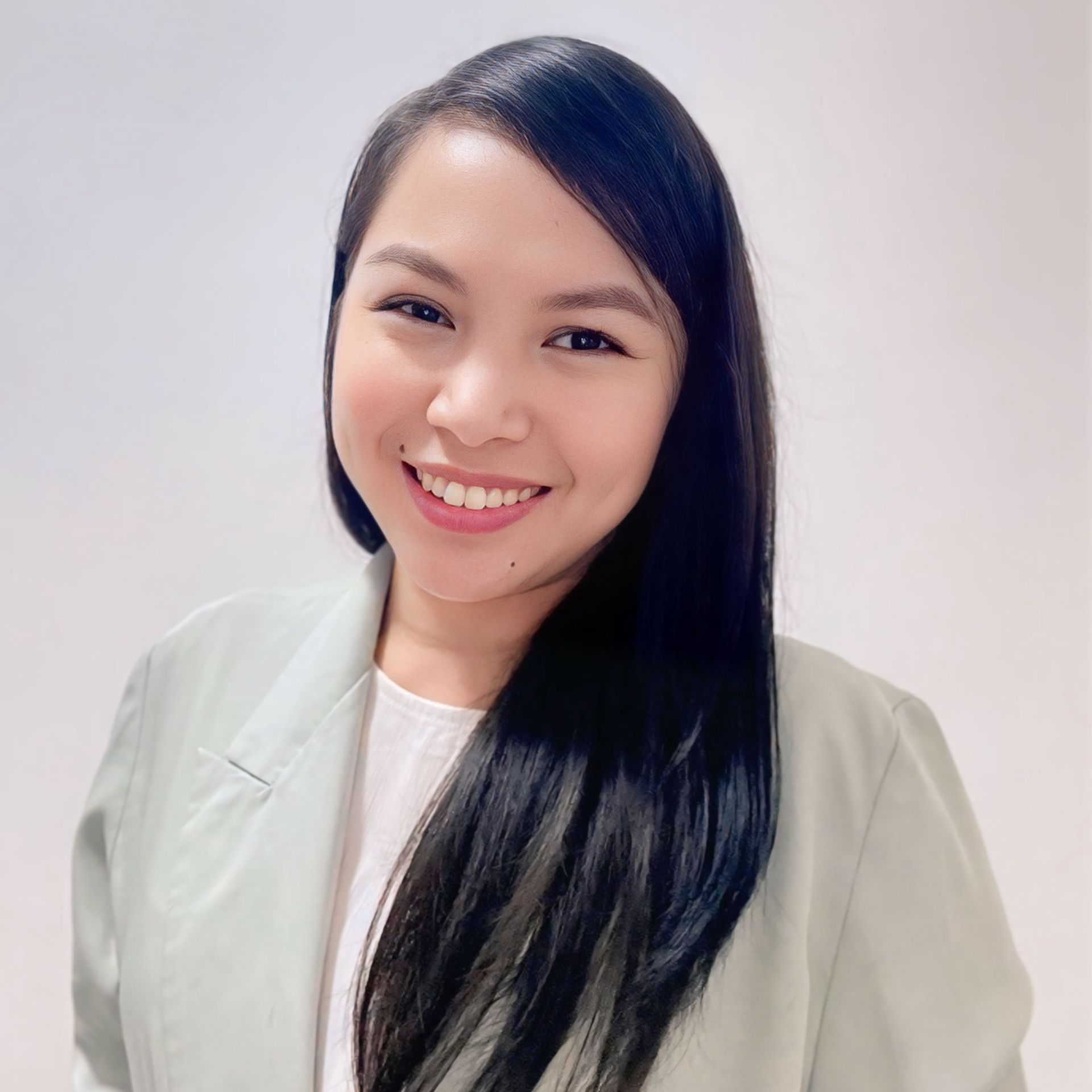A woman wearing a black jacket and a necklace smiles for the camera