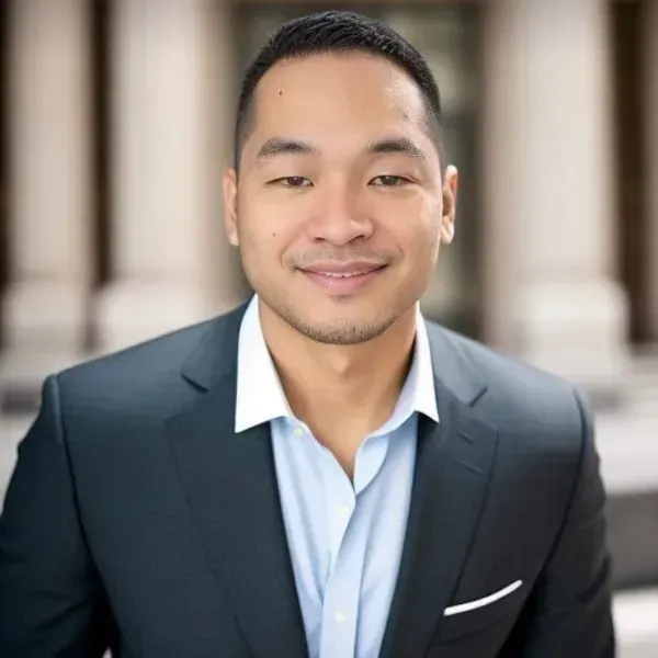 A man in a suit and blue shirt is smiling for the camera.