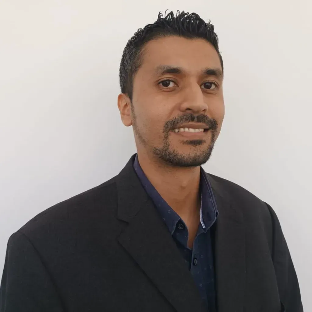 A man with a beard is wearing a suit and smiling for the camera.