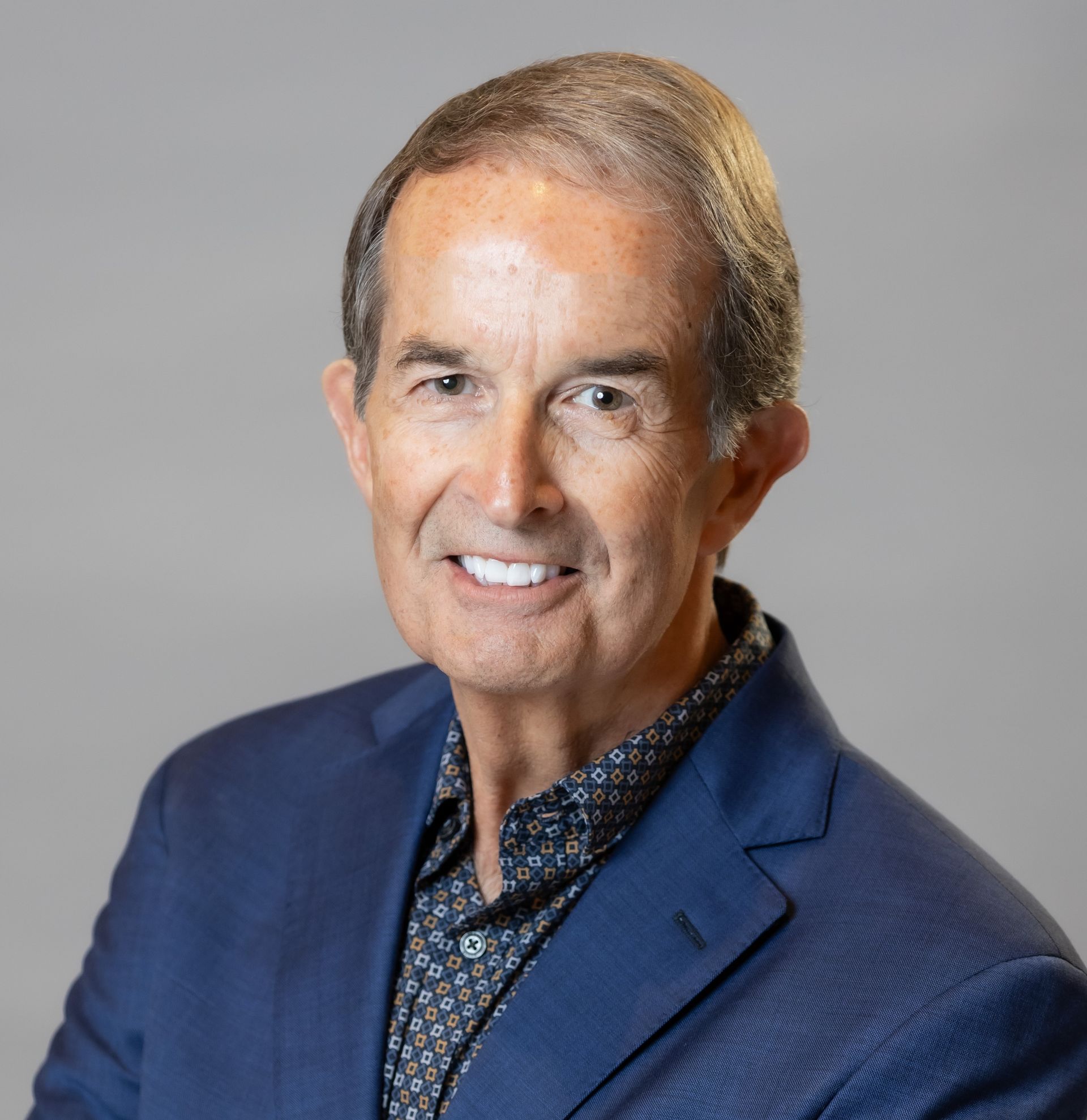 A man in a blue suit and shirt is smiling for the camera.