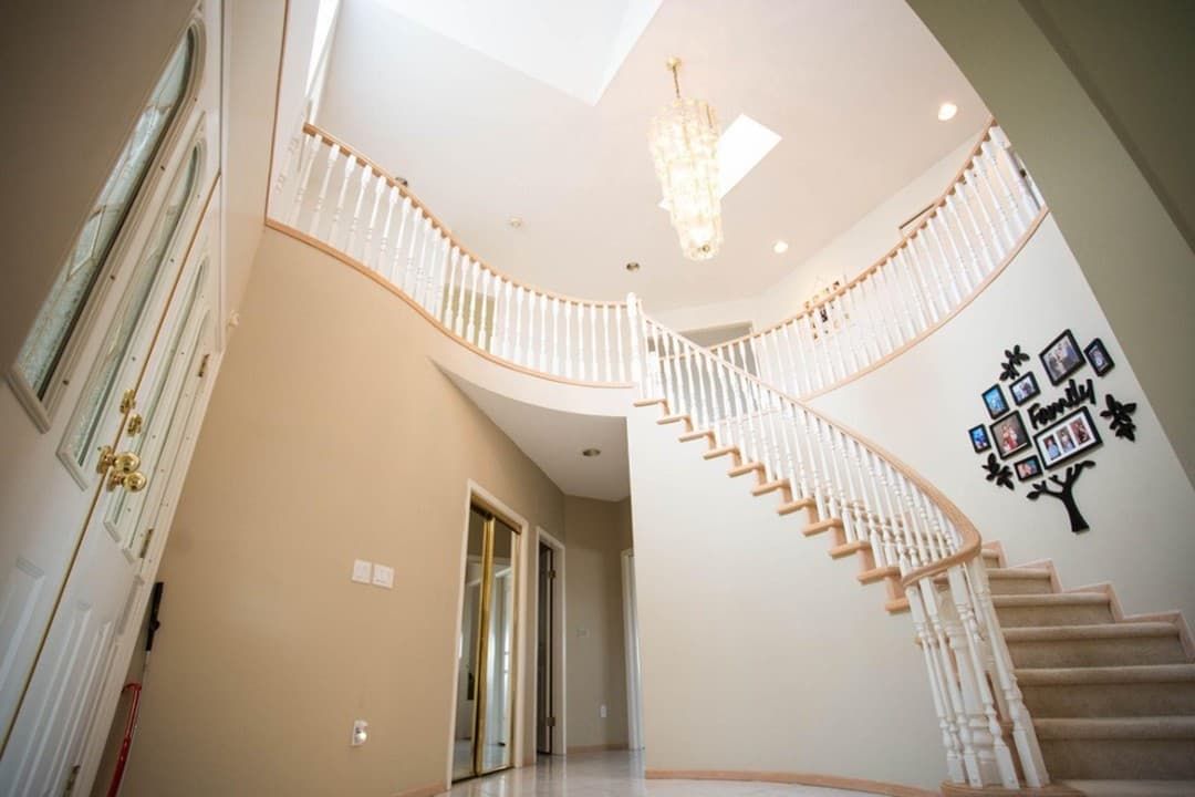 A large hallway with a curved staircase and a chandelier.