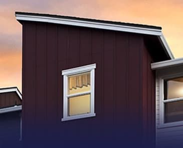 A red house with a white window on the side of it.