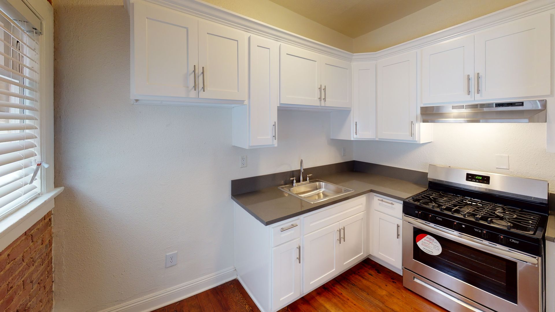 White kitchen cabinets and counters, stainless steel stove, and sink.