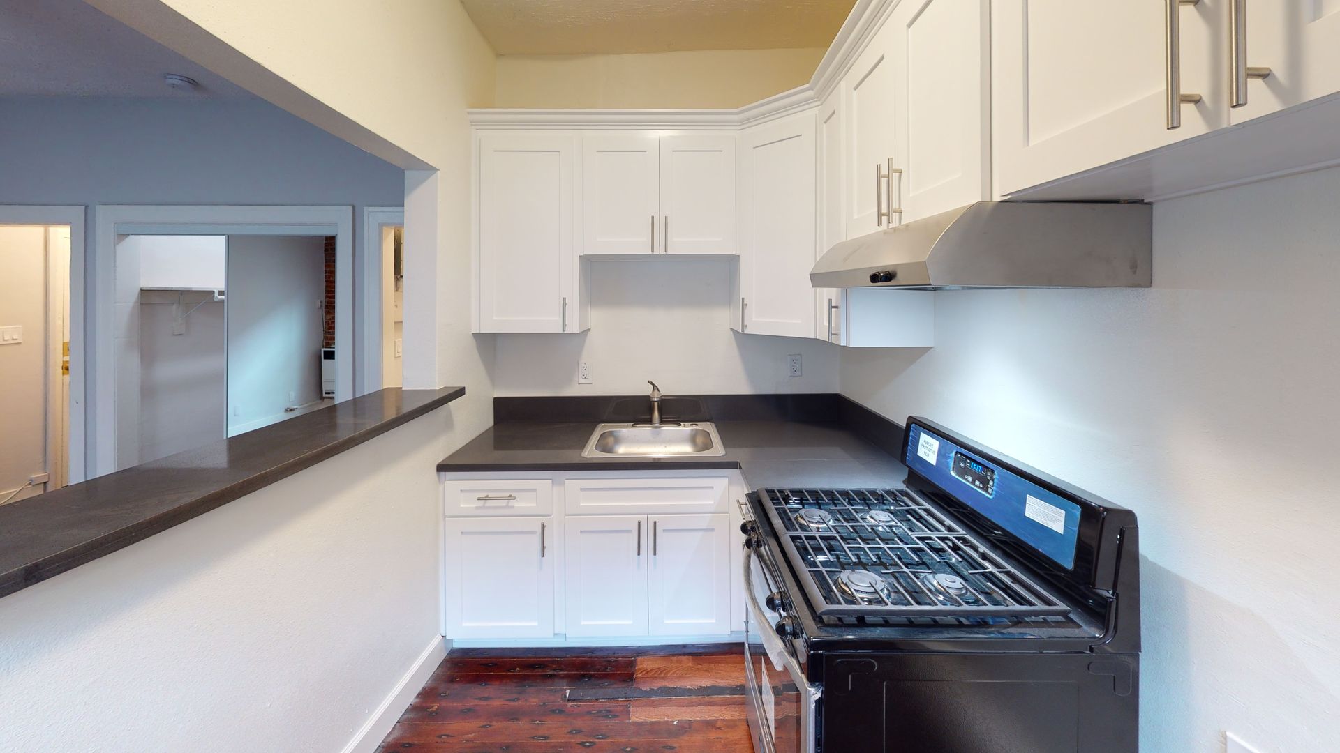 Small kitchen with white cabinets, dark countertops, and a gas stove.