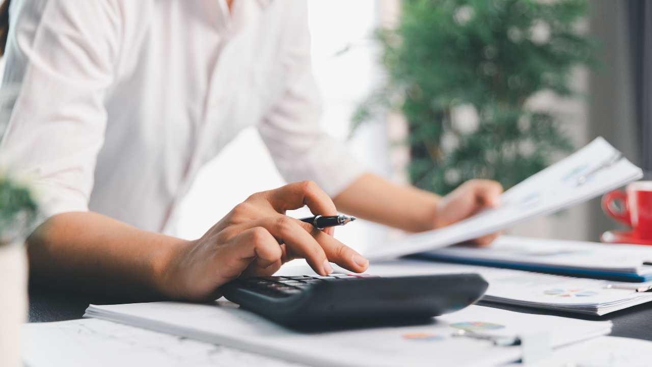 Person using calculator at desk with documents.