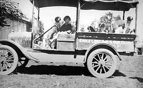 Old truck with several dogs and a person driving. 